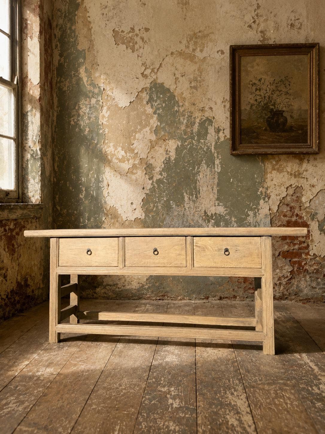 Reclaimed elm console table with three drawers against a distressed plaster wall